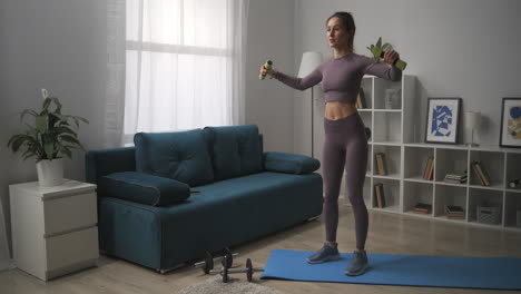 smiling-woman-dressed-sportswear-is-training-with-small-dumbbells-in-living-room-home-workout-for-good-shape-of-body-sportswoman-is-lifting-weights
